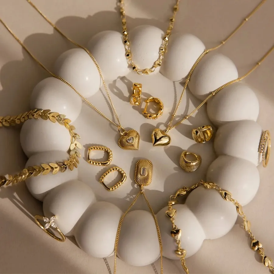 Gold charms, clasps and chains arranged on a white ceramic dish