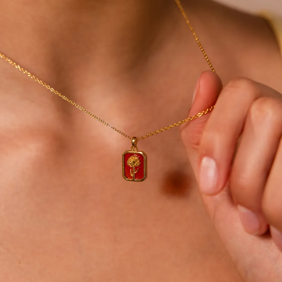 A hand holding the Birth Flower Charm Necklace at the collarbone
