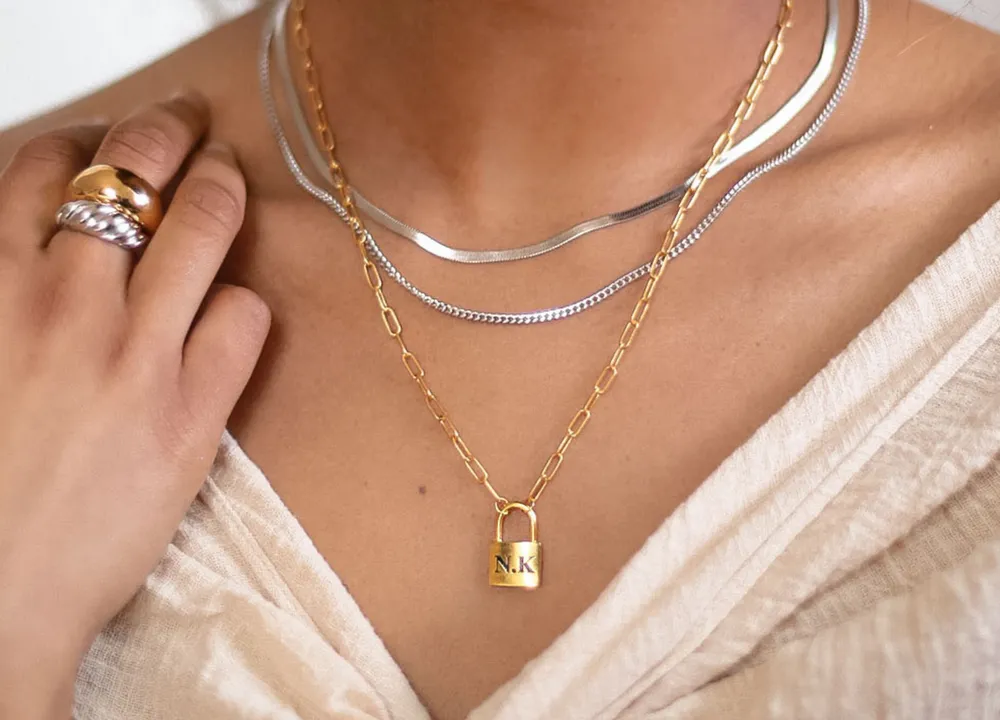 Silver and gold layering necklaces worn together with stacked rings