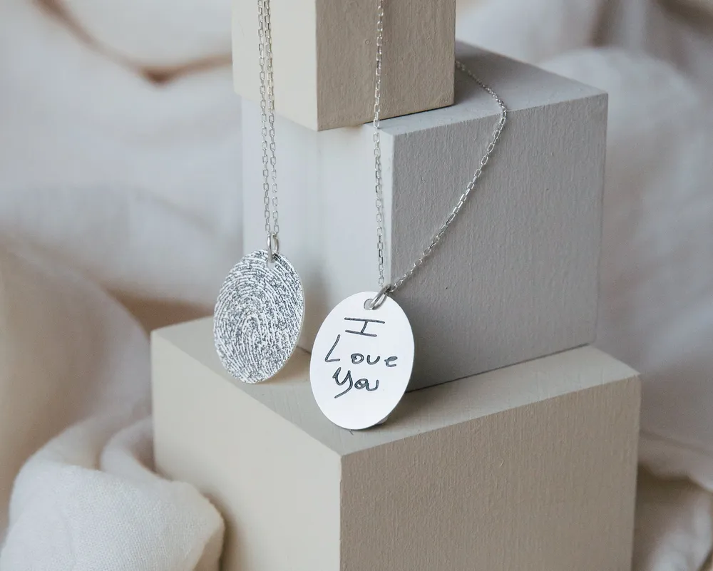 Engraved silver disc pendants, one reading I love you in handwriting, hanging over plaster blocks