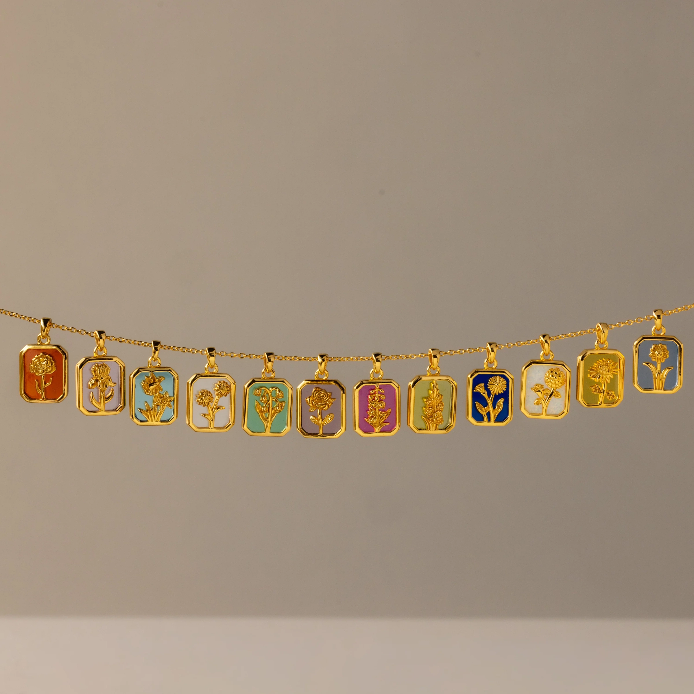 Birth Flower Charm Necklace: a gold chain carrying twelve rectangular flower pendants
